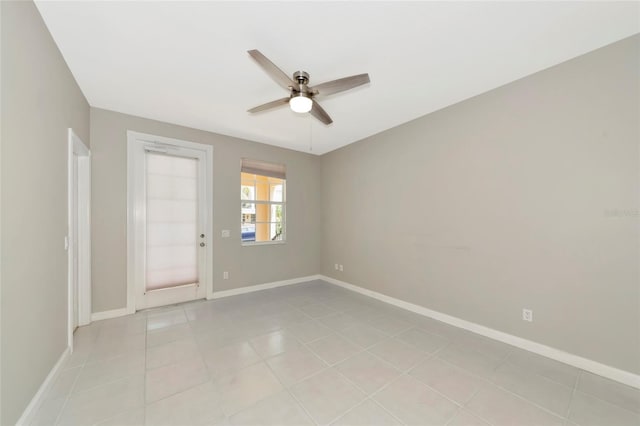 spare room with baseboards, ceiling fan, and light tile patterned floors