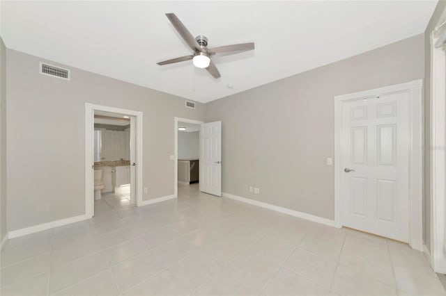 unfurnished bedroom featuring connected bathroom, light tile patterned flooring, baseboards, and visible vents