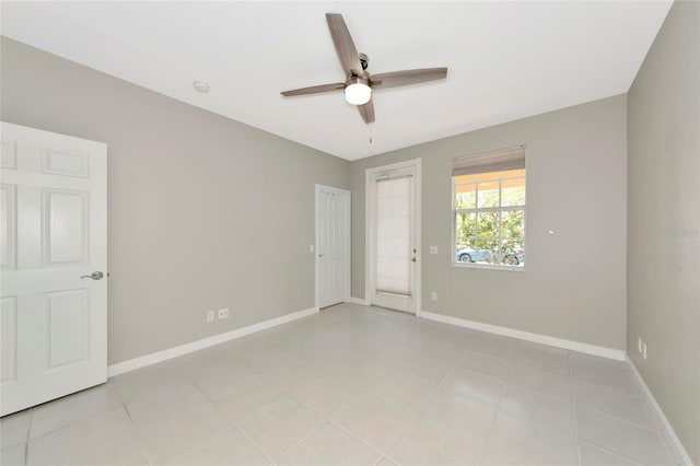 spare room featuring baseboards, ceiling fan, and light tile patterned flooring
