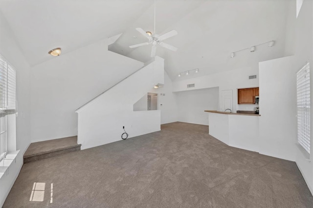 unfurnished living room featuring ceiling fan, visible vents, rail lighting, high vaulted ceiling, and carpet flooring