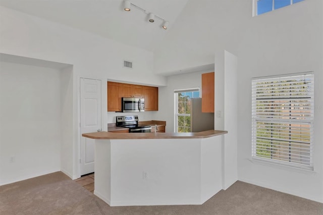 kitchen featuring visible vents, track lighting, high vaulted ceiling, light colored carpet, and appliances with stainless steel finishes