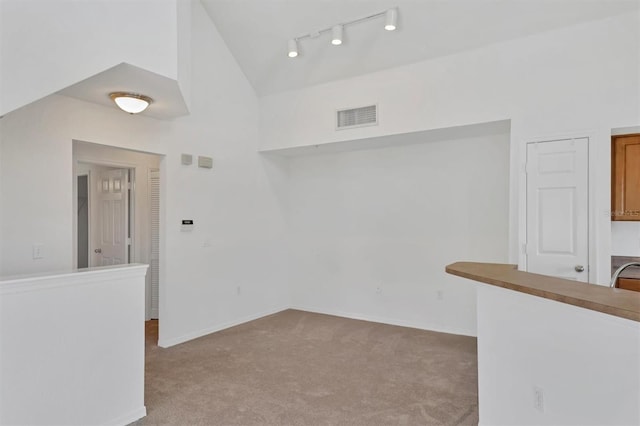interior space featuring visible vents, rail lighting, baseboards, and vaulted ceiling