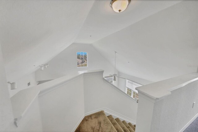 stairway with carpet flooring, baseboards, and lofted ceiling