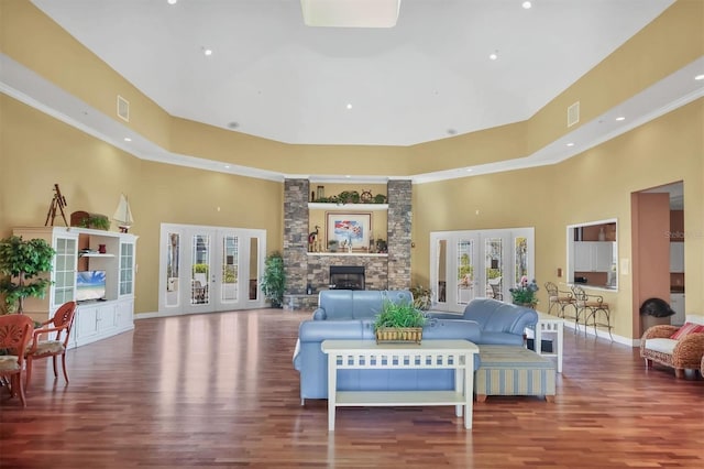 living room featuring visible vents, a stone fireplace, wood finished floors, and a towering ceiling