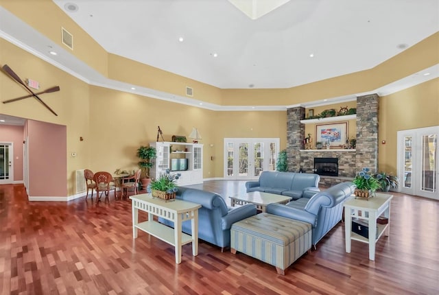 living room with visible vents, a fireplace, wood finished floors, and a towering ceiling