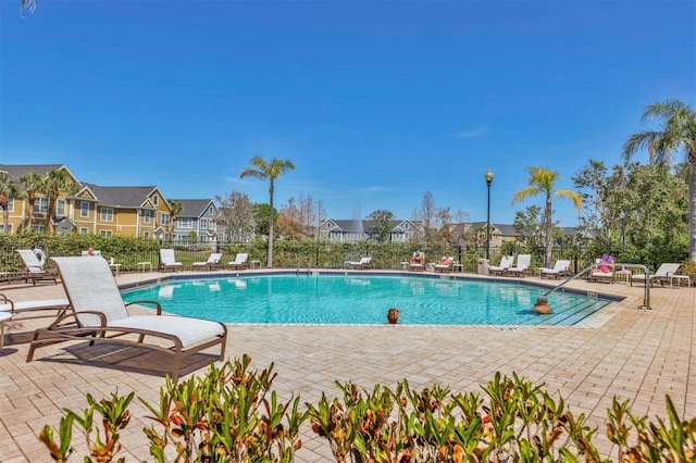 pool featuring a patio, fence, and a residential view