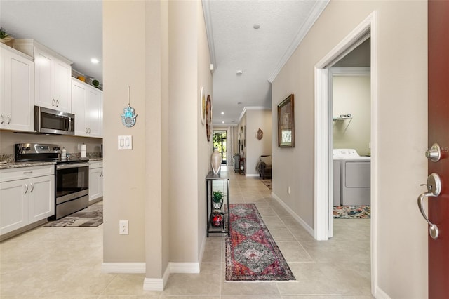 hallway featuring crown molding, baseboards, washer / clothes dryer, and light tile patterned floors