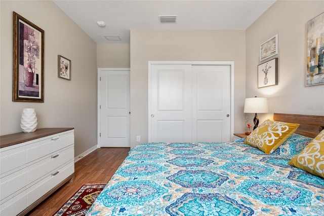 bedroom with visible vents, baseboards, wood finished floors, and a closet