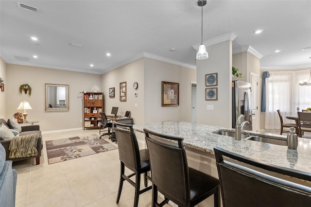 kitchen featuring stainless steel refrigerator with ice dispenser, visible vents, a sink, light stone counters, and recessed lighting