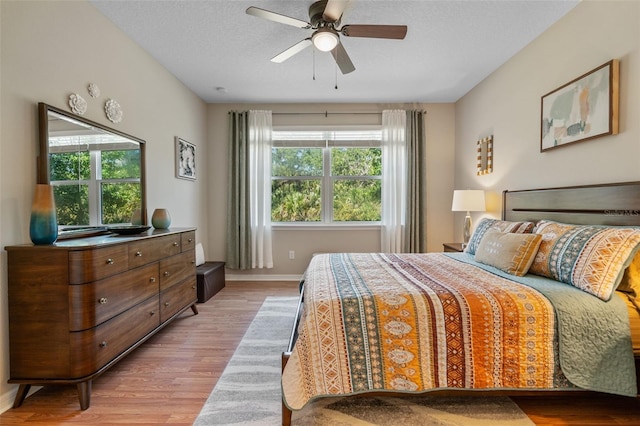 bedroom with light wood-style floors, baseboards, and ceiling fan