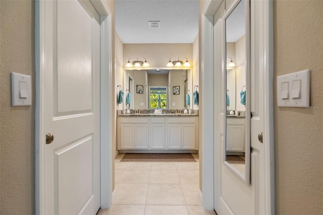 full bath with visible vents, a textured wall, and tile patterned flooring