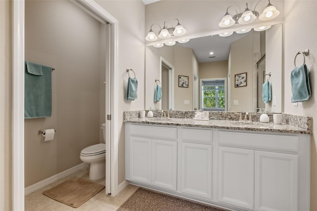 bathroom featuring double vanity, toilet, a sink, and tile patterned flooring