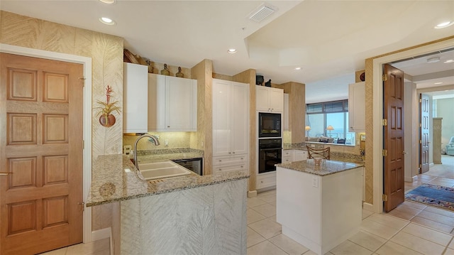 2185 Gulf Of Mexico Dr Unit 243, Longboat Key, FL 34228 - kitchen with black appliances, a sink, white cabinetry, light stone countertops, and a peninsula