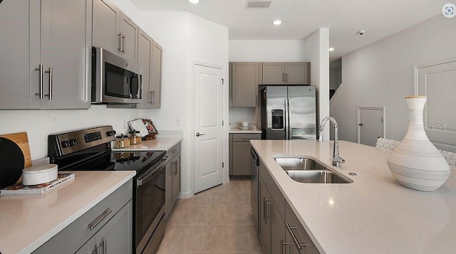 kitchen featuring a sink, light countertops, gray cabinets, and stainless steel appliances