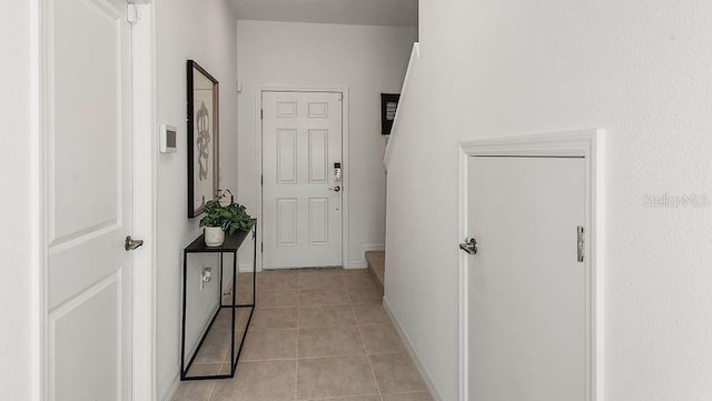 corridor featuring light tile patterned floors and baseboards