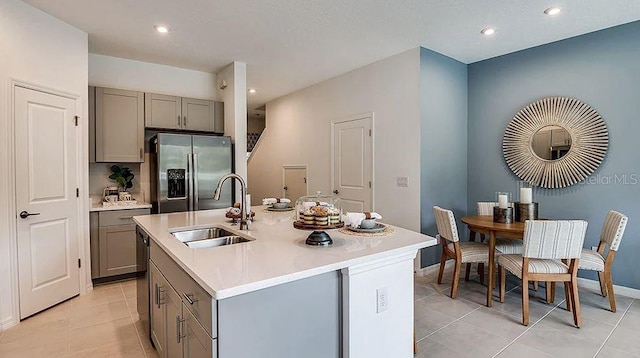 kitchen with a sink, gray cabinets, light tile patterned floors, and stainless steel fridge with ice dispenser