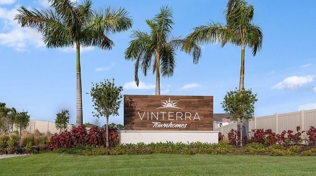 community / neighborhood sign with fence and a yard