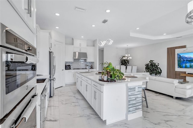 6203 Grandview Hill Ct, Bradenton, FL 34203 - kitchen featuring under cabinet range hood, a kitchen bar, decorative backsplash, light marble finish flooring, and recessed lighting