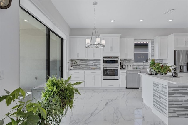 6203 Grandview Hill Ct, Bradenton, FL 34203 - kitchen featuring stainless steel appliances, light countertops, tasteful backsplash, white cabinets, and a chandelier