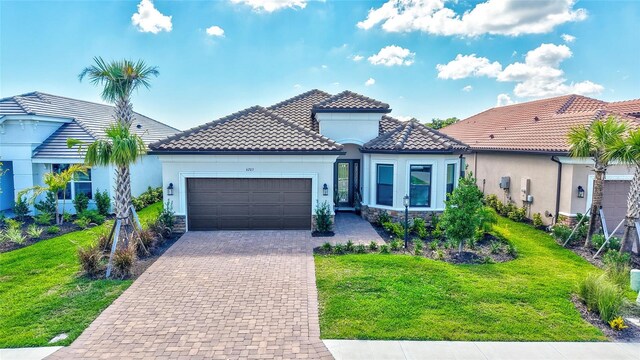 6203 Grandview Hill Ct, Bradenton, FL 34203 - mediterranean / spanish home featuring an attached garage, decorative driveway, a front lawn, and stone siding