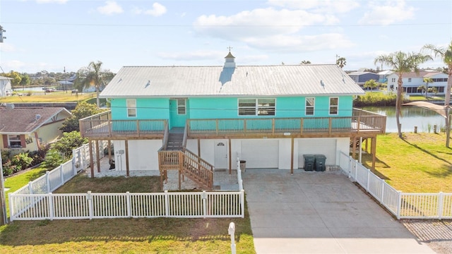 view of front facade featuring metal roof, a residential view, a front lawn, concrete driveway, and stairs