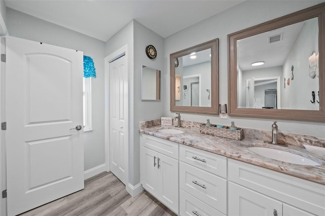 bathroom featuring a sink, baseboards, wood finished floors, and visible vents