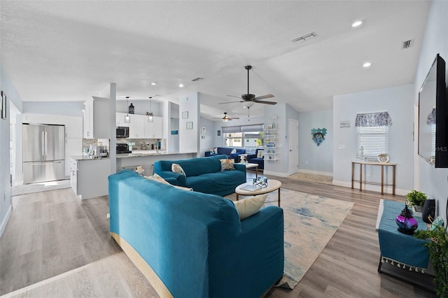living area featuring baseboards, visible vents, ceiling fan, and lofted ceiling