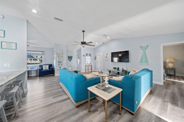 living room with baseboards, ceiling fan, wood finished floors, and lofted ceiling