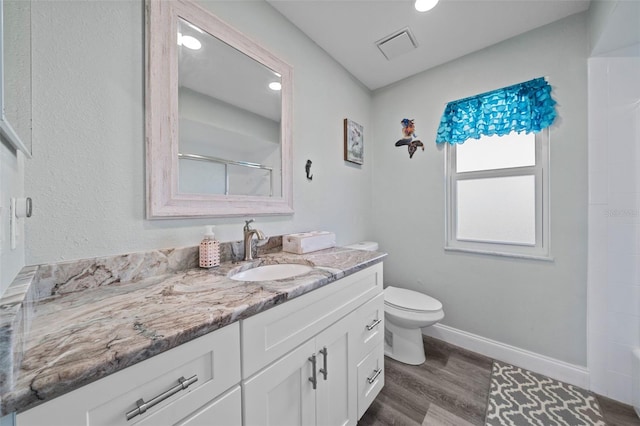 bathroom featuring vanity, wood finished floors, toilet, baseboards, and walk in shower