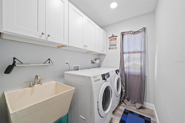 laundry area featuring wood finished floors, washing machine and dryer, baseboards, a sink, and cabinet space