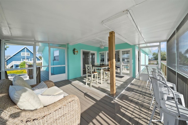 sunroom featuring outdoor dining area, ceiling fan, and a wealth of natural light