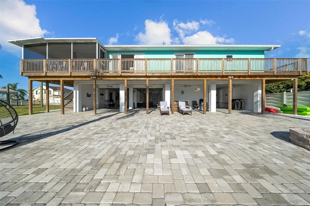 back of property featuring ceiling fan, a wooden deck, stairs, a sunroom, and a patio area