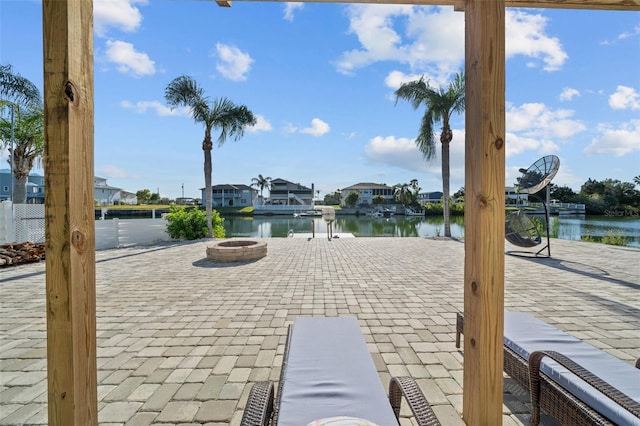 view of patio / terrace featuring a residential view, a water view, and a fire pit