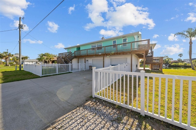exterior space featuring concrete driveway, a deck, stairs, and a front lawn