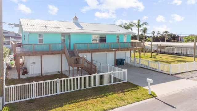 view of front of property with a garage, a front lawn, a fenced backyard, driveway, and stairway