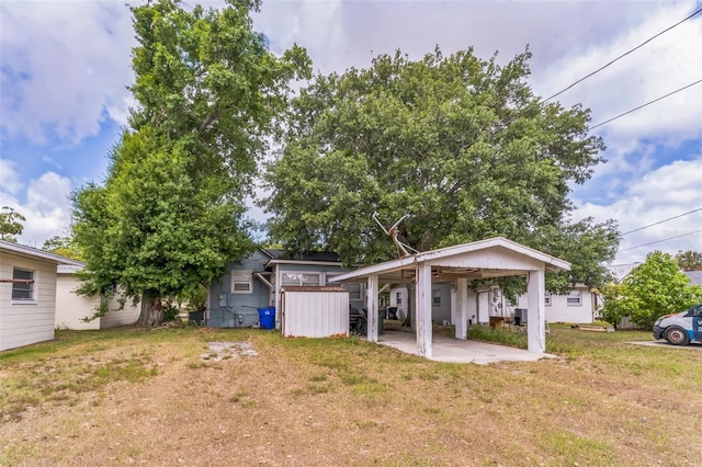 rear view of property with a lawn, an outbuilding, a carport, and a shed