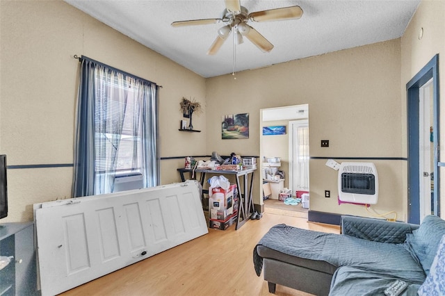 interior space featuring a ceiling fan, a textured ceiling, heating unit, and light wood-style floors