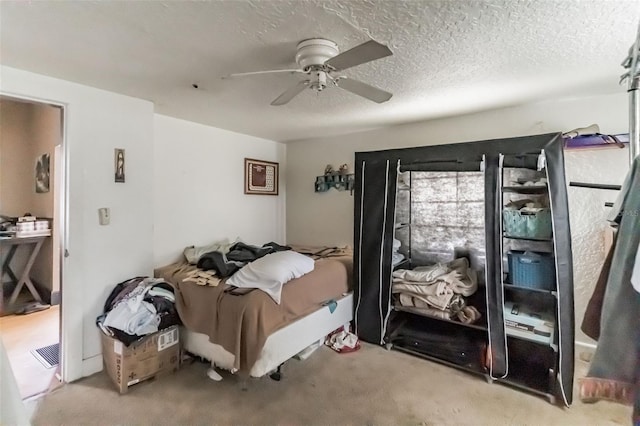 carpeted bedroom featuring a ceiling fan and a textured ceiling