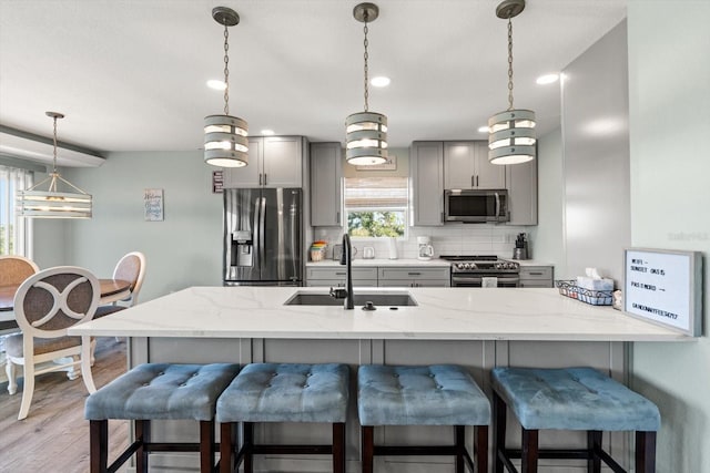 4717 Lemon Bay Dr, Venice, FL 34293 - kitchen with decorative backsplash, a kitchen breakfast bar, a sink, appliances with stainless steel finishes, and gray cabinetry