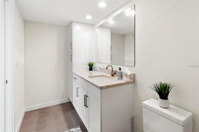 half bathroom featuring vanity, baseboards, toilet, and recessed lighting