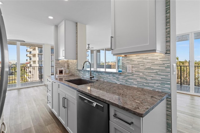 kitchen with backsplash, stone counters, a sink, and dishwasher