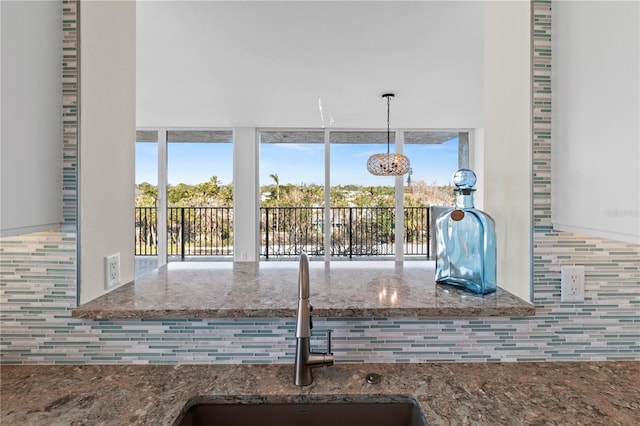 kitchen featuring plenty of natural light, a sink, stone counters, and tasteful backsplash