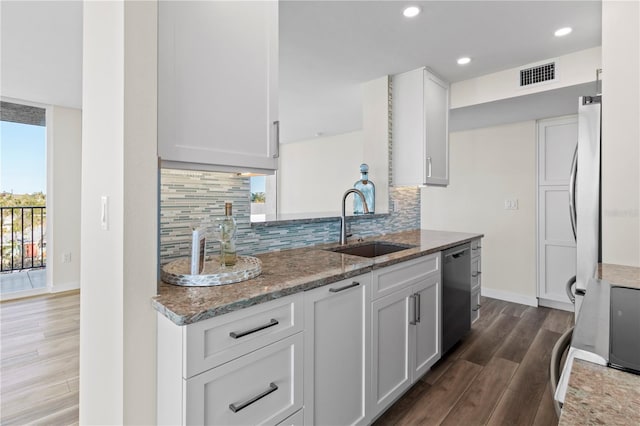 kitchen with light stone countertops, a sink, dishwasher, dark wood finished floors, and visible vents