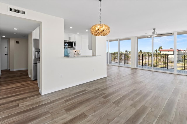 unfurnished living room featuring visible vents, a wealth of natural light, and wood finished floors