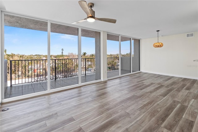 spare room featuring visible vents, ceiling fan, wood finished floors, and expansive windows