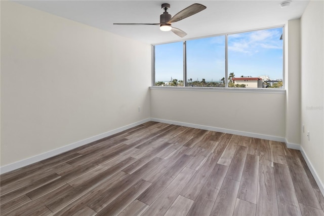 spare room with baseboards, ceiling fan, and wood finished floors