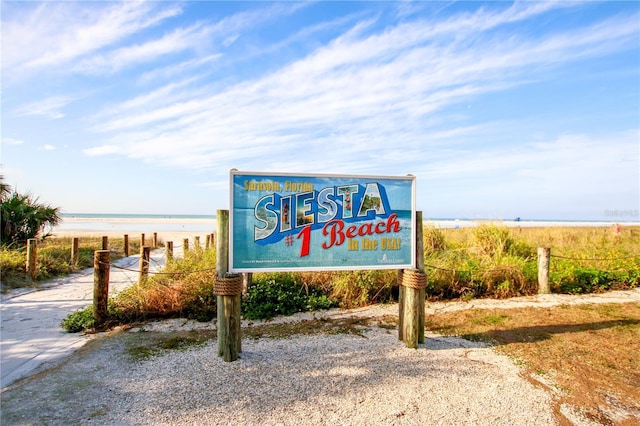 community sign with a water view and a view of the beach