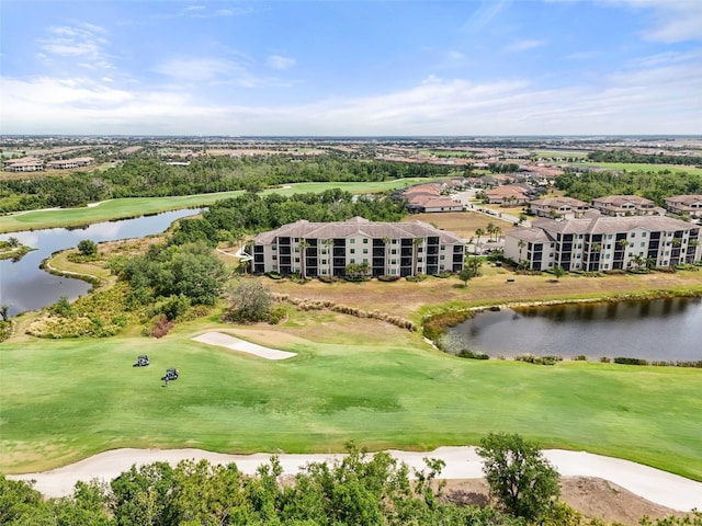 bird's eye view of a local golf course, a nearby body of water, and apartment complex / building