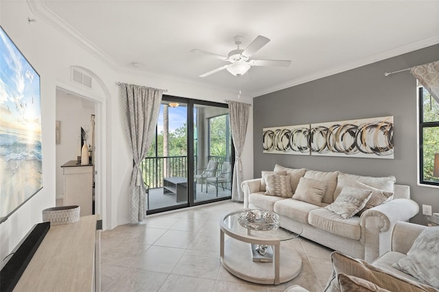 living area featuring healthy amount of natural light, ceiling fan, light tile patterned flooring, and ornamental molding
