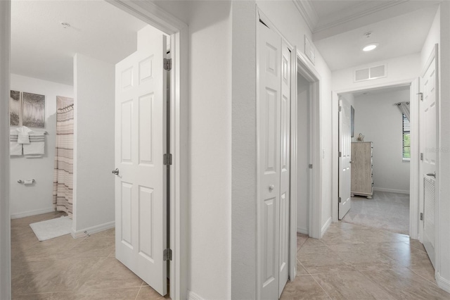 hall featuring ornamental molding, baseboards, and light tile patterned floors
